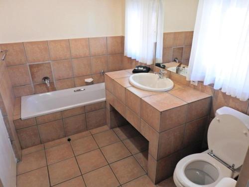a bathroom with a tub and a sink and a toilet at Fairways Holiday Accommodation in Drakensberg Garden