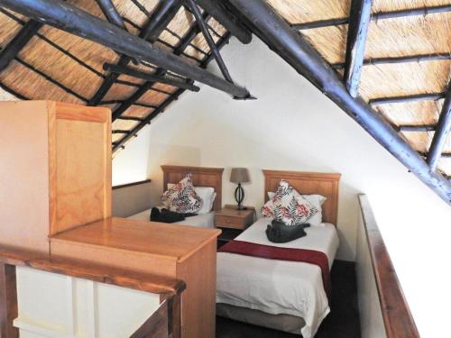 a bedroom with two beds and a table with a lamp at Fairways Holiday Accommodation in Drakensberg Garden