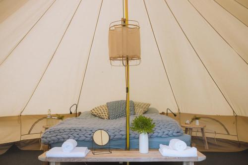 レクサンドにあるSjugare Gård Glampingのテント内ベッド1台 テーブルに帽子2つ付