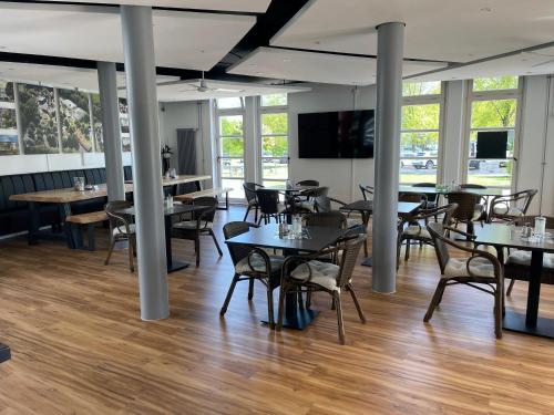 a dining room with tables and chairs and windows at TAT Tagungs- und Gästehaus in Rheine