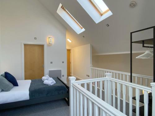 a bedroom with a bed and a staircase with a skylight at Modern Duplex Apartment with Woodland Views in Swansea