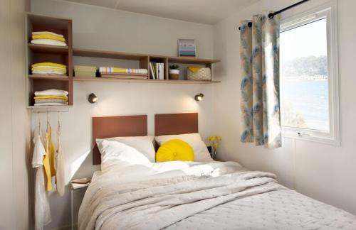 Dormitorio con cama con almohada amarilla en Camping Les Sables Blancs, en Concarneau