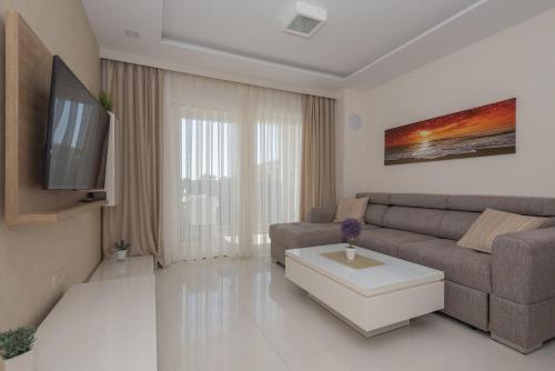 a living room with a couch and a tv at Promajna Leone Erceg Apartments in Promajna