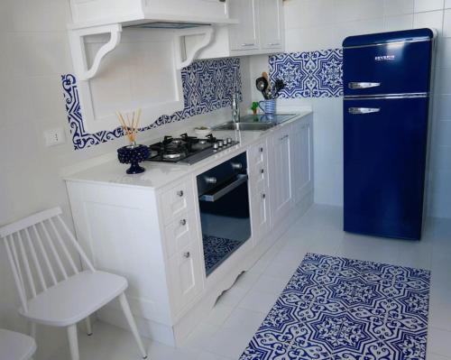 uma cozinha com armários brancos e um frigorífico azul em Casa Marrapese em Positano