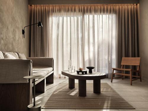 a living room with a couch and a table in front of a window at Lindian Village All Inclusive Resort Rhodes,Curio Collection in Kiotari