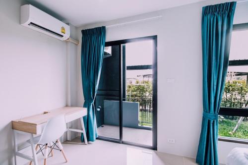 um quarto com uma secretária e uma janela em The Living Hotel SamutPrakan em Bang Bo