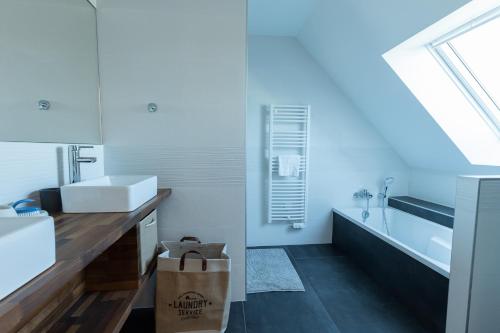 La salle de bains blanche est pourvue d'un lavabo et d'une baignoire. dans l'établissement Villa Nymphéa - maison avec piscine chauffée St Gildas de Rhuys, à Saint-Gildas-de-Rhuys