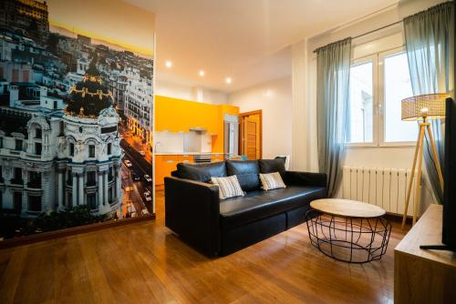 ein Wohnzimmer mit einem schwarzen Sofa und einem Tisch in der Unterkunft Smartr Madrid Atocha in Madrid