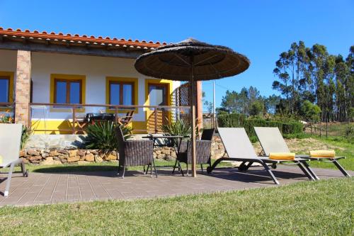 a patio with a table and chairs and an umbrella at Quinta das Alfambras in Aljezur
