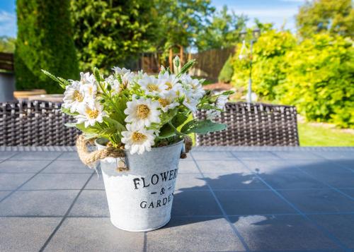 a bucket with flowers in it sitting on the ground at Valley Vendégház in Eger