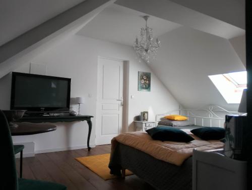 ein Wohnzimmer mit einem Bett und einem TV in der Unterkunft La Menardière L'appart' in Corseul