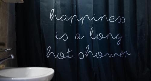 a bathroom with a shower curtain that reads happiness is a long hot shower at Central apartment with parking in Larisa