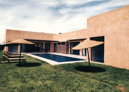Villa lumias في مراكش: مسبح مع مظلتين في العشب
