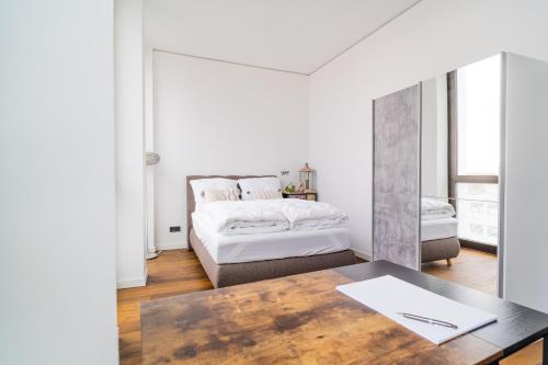 a white bedroom with a bed and a table at Panorama Bliss - Luxus Apartment in Braunschweig's Altstadt in Braunschweig