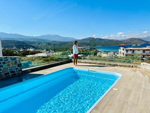 una donna in piedi sul bordo di una piscina di Villa Praxia i a Kalo Chorio