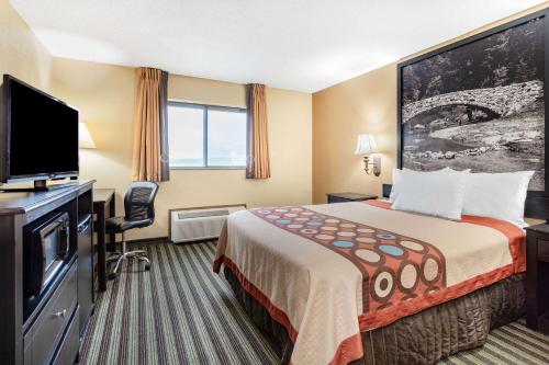 a hotel room with a bed and a flat screen tv at Super 8 by Wyndham Iowa Falls in Iowa Falls
