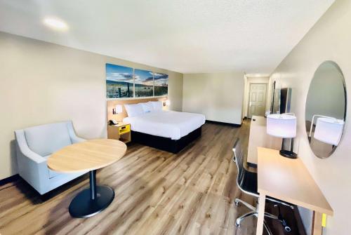 a hotel room with a bed and a desk and a table at Days Inn by Wyndham Burleson Ft. Worth in Burleson