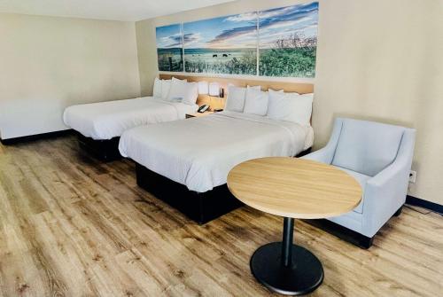 a hotel room with two beds and a table and a chair at Days Inn by Wyndham Burleson Ft. Worth in Burleson