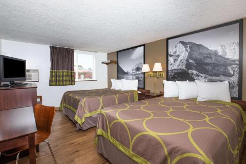 ein Hotelzimmer mit 2 Betten, einem Schreibtisch und einem TV in der Unterkunft Super 8 by Wyndham Missoula/Brooks Street in Missoula