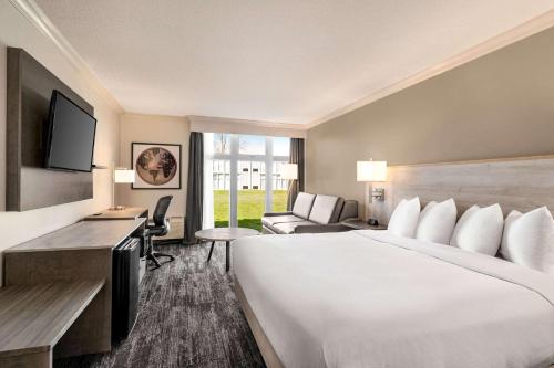 una camera d'albergo con un grande letto e una scrivania di Ramada by Wyndham Cornwall a Cornwall