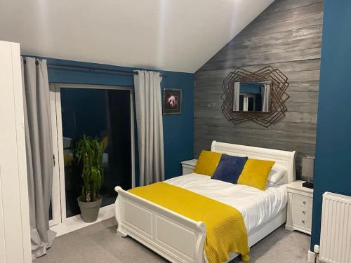 a bedroom with a white bed with yellow and blue pillows at Casblaidd in Caernarfon