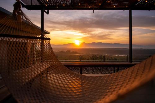 a hammock in a house with a sunset in the background at Ao Luek Panoramic Pool-SHA Plus in Ao Luk