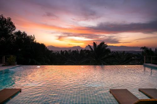 a large swimming pool with a sunset in the background at Ao Luek Panoramic Pool-SHA Plus in Ao Luk