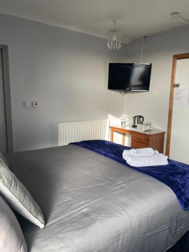 a bedroom with a bed with a tv on the wall at Whiteways Guest House in Skegness