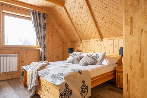 um quarto com uma cama num chalé de madeira em Góralskie Domki Zakopane Gubałówka em Zakopane