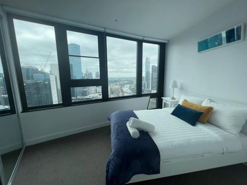 a white bed in a room with large windows at Pars apartments - Melbourne Quarter- unique View of city and Yarra in Melbourne