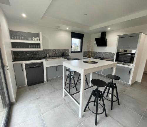 a kitchen with a white island and stools in it at Grand Gîte de Kergroas in Ploumilliau