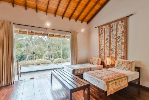 a living room with two beds and a large window at Villa Hundira in Negombo