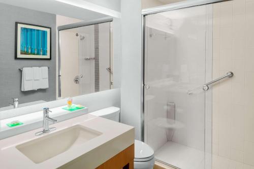 La salle de bains blanche est pourvue d'un lavabo et d'une douche. dans l'établissement Hyatt Place Athens Downtown, à Athens