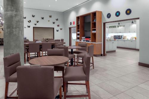 a restaurant with tables and chairs and a kitchen at Hyatt Place Athens Downtown in Athens