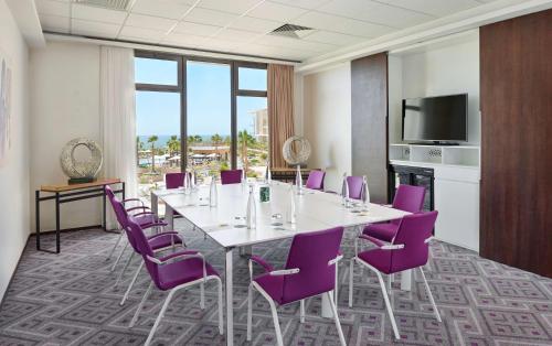 a conference room with a table and purple chairs at Hyatt Place Taghazout Bay in Taghazout