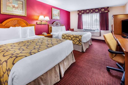 a hotel room with two beds and a desk at Baymont by Wyndham Perrysburg-Toledo in Perrysburg