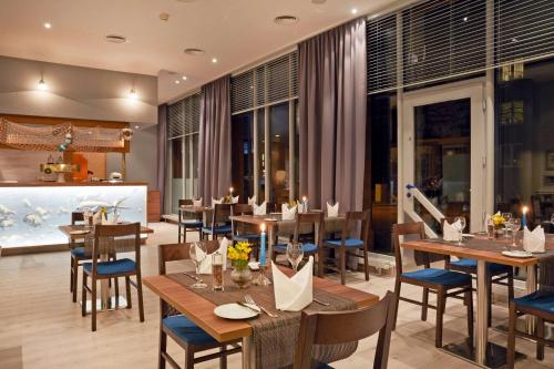 a restaurant with wooden tables and chairs and windows at H4 Hotel Hamburg Bergedorf in Hamburg