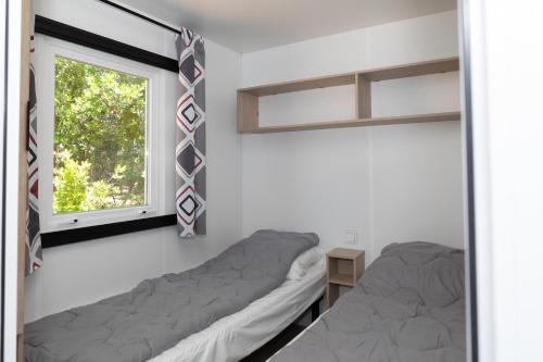 - une chambre avec 2 lits et une fenêtre dans l'établissement CAMPING LES OURMES, à Hourtin