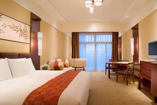 a hotel room with a bed and a desk at Wyndham Grand Tianjin Jingjin City in Tianjin