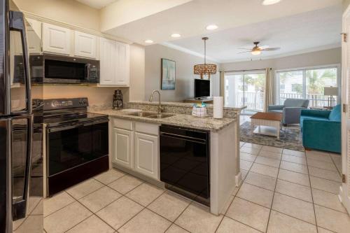 eine Küche mit schwarzen Geräten und ein Wohnzimmer in der Unterkunft Palm Beach Resort Orange Beach a Ramada by Wyndham in Orange Beach