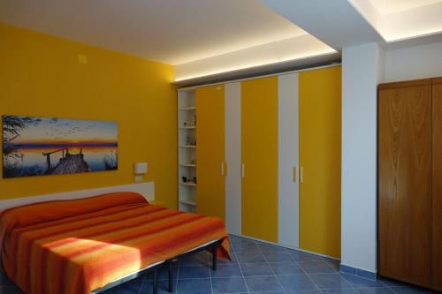 ジョイオーザ・マレーアにあるCasa Gioiosaのベッドルーム1室(黄色い壁、オレンジのシーツが備わるベッド1台付)