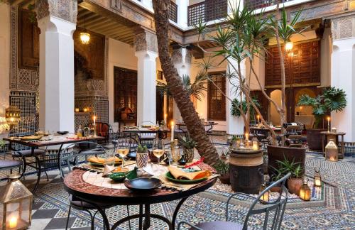 un ristorante con tavoli, sedie e palme di Marrakech Riads, Angsana Heritage Collection a Marrakech