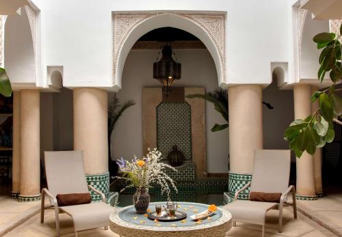 Marrakech Riads, Angsana Heritage Collection في مراكش: لوبي مع طاولة وكراسي ومبنى