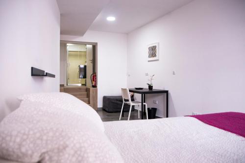 Habitación blanca con cama y escritorio en Sensacional Apartamento Saladina Home, en Ourense