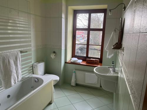 a bathroom with a tub and a toilet and a sink at Gościniec Zamkowy in Darłowo