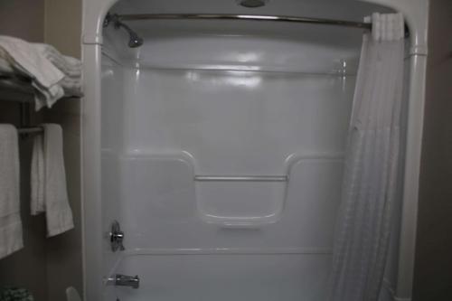 W łazience znajduje się biały prysznic z zasłoną prysznicową. w obiekcie Days Inn by Wyndham Waco University Area w mieście Waco