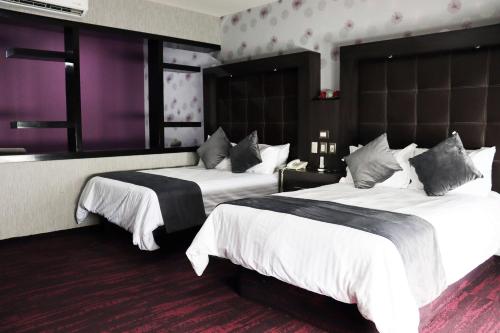 Habitación de hotel con 2 camas y paredes moradas en Wyndham Garden Aguascalientes Hotel & Casino, en Aguascalientes