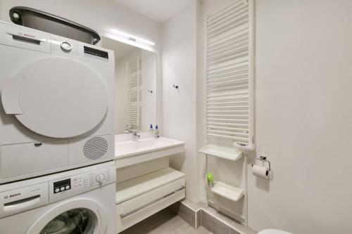 a white bathroom with a washing machine and a sink at Apartment Parking and terrace - 20 min from Paris in Maisons-Alfort