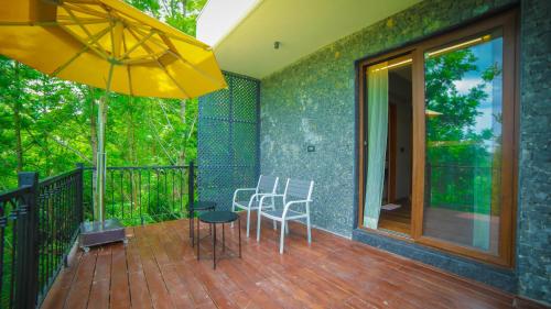 a balcony with two chairs and a table and an umbrella at Grand Palace Hotel & Spa in Yercaud