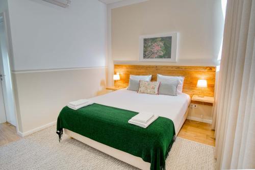 a bedroom with a large bed with a green blanket at Casa das Letras - Turismo rural in Ponte da Barca